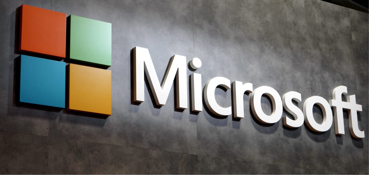  The image shows the Microsoft logo in 3D on a textured concrete background.