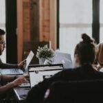 A group of team members is gathered around a table, conducting market research.